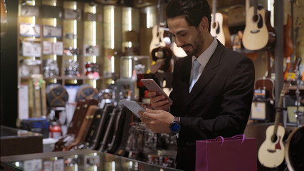 An upwardly mobile Middle Eastern man using a mobile phone - smartwatch to purchase product at the point of sale terminal in a retail store with nfc identification payment for verification