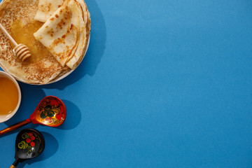 Tasty homemade pancakes with honey on a blue background. Top view, close-up. Traditional holiday celebration concept. Russian translation wide and happy Shrovetide Maslenitsa.