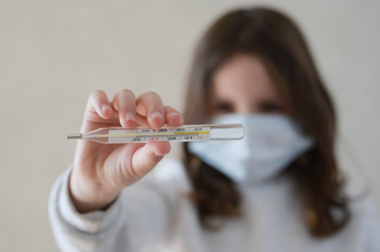 Coronavirus Danger COVID-19 Epidemic Outbreak Quarantine Concept Of Little Girl In Medical Mask Holding Thermometer With High Level Of Temperature