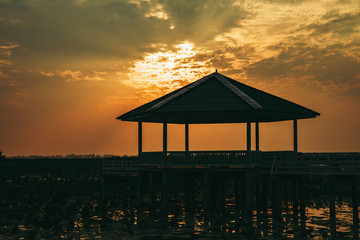 Vintage Wooden Pavilion is under construction with light from sunset or evening time at water lake of public park of Bueng See Fai, Phichit Province, Thailand.