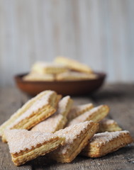 Homemade shortbread puff pastry Triangle in a brown plate on a wooden ancient background. Side view. Place for text.