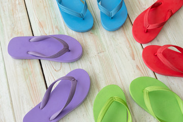 purple , Red , green , blue flip flops on wooden background. Top view