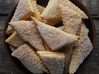 Homemade shortbread puff pastry triangle in a brown plate on a wooden ancient background. Top view. Place for text.