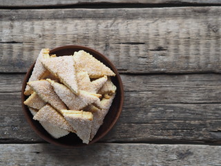 Homemade shortbread puff pastry triangle in a brown plate on a wooden ancient background. Top view. Place for text.