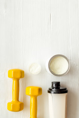 Obraz na płótnie Canvas Sport diet. Protein shake near dumbbells on white background top-down flat lay copy space