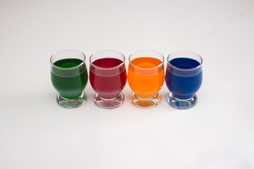 Liquid colored dyes in a glass goblet for coloring various objects, such as Easter eggs or for children's creativity.