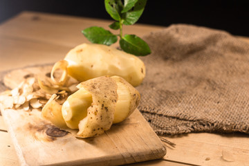 Peeled potatoes with the peel a on a wooden table.