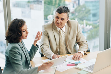 Business people discussing report on tablet computer when working on development strategy