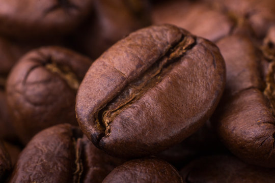 macro of brown beans of roasted aromatic coffee on a black background