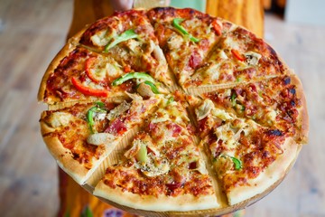 Supreme pizza, set on the round wooden plate and dried oregano on top. Images.