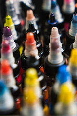 selective focus vertical shot of bottles of tattoo ink