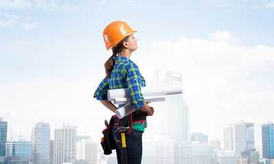 Female engineer in hardhat standing with blueprint