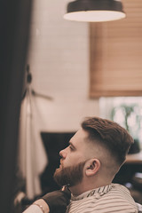 Handsome man with a beard in barbershop. Barber with a client