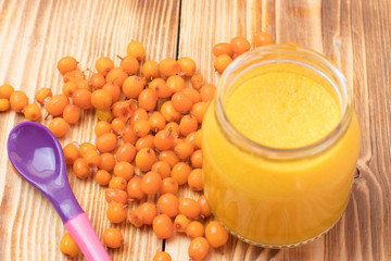 baby sea buckthorn puree in a jar on a wooden table. baby food.