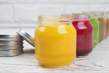 Assortment of jars with tasty baby food on wooden table. vegetable and fruit purees.
