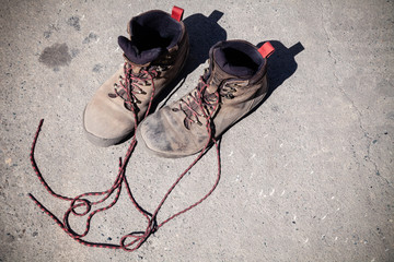 Fototapeta premium Pair of favorite, worn and dirty high-altitude trekking boots covered in mud and shoelaces, top view. Concept travel, hiking, walking in mountains.