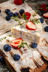 Blue and brie cheese. On a wooden background. served with blueberry and strawberry. The concept of eco products. Background image. Copy space
