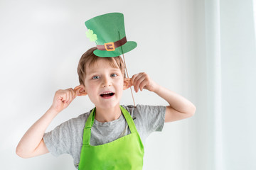 St Patrick's Day holiday concept. Joyful emotional caucasian blond boy with green paper leprechaun...