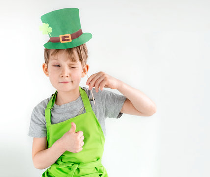 St Patrick's Day holiday concept. Joyful emotional caucasian blond boy with green paper leprechaun hat with clover on white background