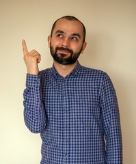 Naklejka premium Portrait of young Turkish man has an idea, pointing with finger up looking up. Thoughtful guy solved a problem problem. Face expression,body language, life perception creativity
