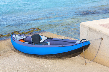Chained blue canoe at coast with sea