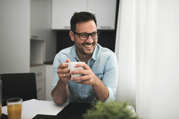 Handsome man having cup of coffee at home in the morning