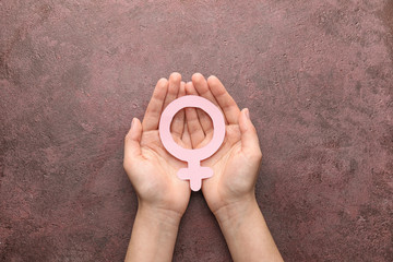 Female hands with symbol of woman on color background. Concept of feminism