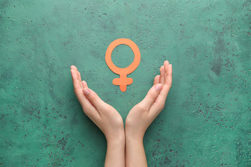 Female hands with symbol of woman on color background. Concept of feminism