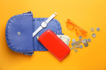 Purse with wallet, money and accessories on color background