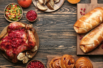 Frame made of tasty baked turkey and different food for Thanksgiving day on wooden table