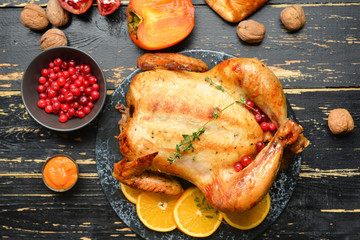 Tasty baked turkey for Thanksgiving day on dark wooden table