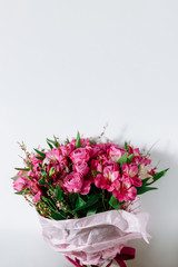 Flower bouquet of pink roses and other mixed flowers wrapped in soft pink paper