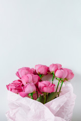 Flower bouquet of pink roses and other mixed flowers wrapped in soft pink paper. Close up, white background, copy space