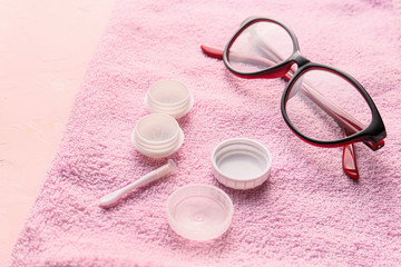 Glasses and container for contact lenses on towel