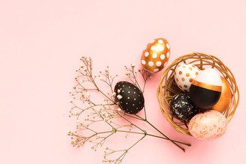 Frame made of wooden painted eggs in gold, black and rose colors on pink background. Happy easter...