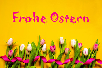 German Text Frohe Ostern Means Happy Easter. White And Pink Tulip Spring Flowers With Ribbon. Yellow Wooden Background
