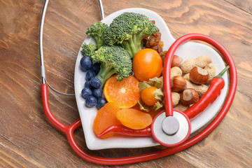 Plate with healthy products and stethoscope on wooden table