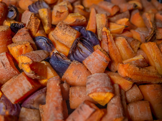 Close up of a tray of oven roasted carrots and red onion covered in an aromatic spice powder