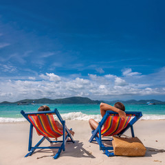 Couple on tropical beach in loungers