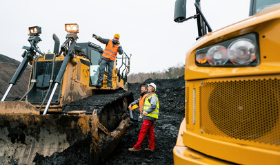 Heavy machinery and workers in pit of quarry