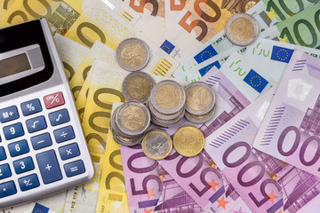 Euro banknotes as background for coins and calculator