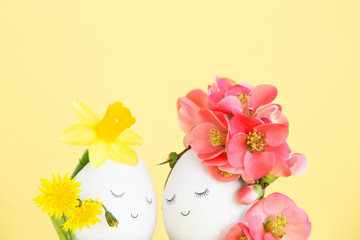 Lovely couple of Easter eggs with drawn faces closed their eyes, decorated with spring flower and wildflowers. Creative concept