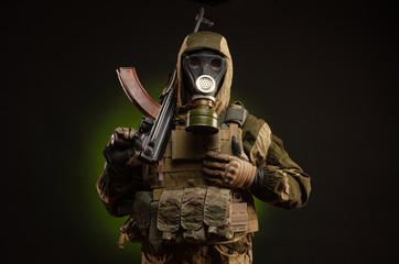 soldier Stalker saboteur in military uniform with a Kalashnikov rifle on a dark background in a gas mask - obrazy, fototapety, plakaty
