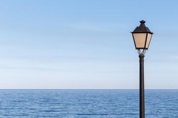 Streetlamp off on a sunny day and the calm sea in the background