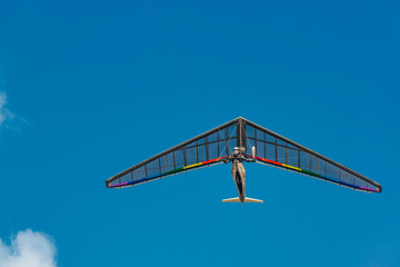 Bright rainbow colored hang glider wing in flight.
