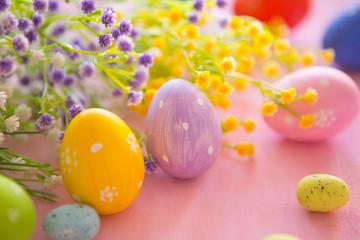 Easter eggs with spring blossom flowers on pink wooden background.