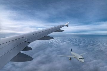 Wing of jet and airplane fly in sky above clouds. View from plane window