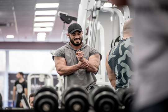 strong muscle bearded caucasian athlete man holding his wrist with hand during sport training injury with grimace of pain on his face indoor gym