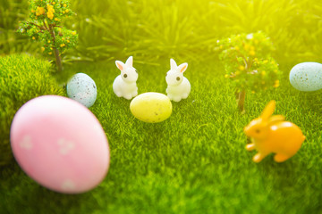 Easter decorate with rabbit toy and Easter eggs on grass field background