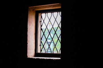 View of the tower of the Church of St. Wenceslaus in Loket, in Czech Republic, through the grills of a window from Loket Castle